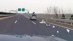 Un coffre de toit s'ouvre et disperse des affaires sur l'autoroute